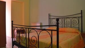 A single bed with a metal frame and a striped bedspread in a room with a plain wall and a radiator. - Hotel Scalea (Scalea)