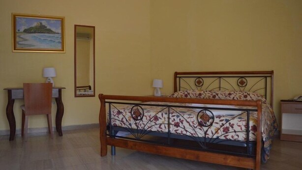 A bedroom with a bed, a desk, a chair, a mirror, and a painting on the wall. - Hotel Scalea (Scalea)