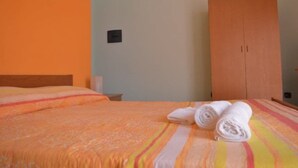 A hotel room with a bed, a wooden wardrobe, and a wall-mounted light switch. - Hotel Scalea (Scalea)