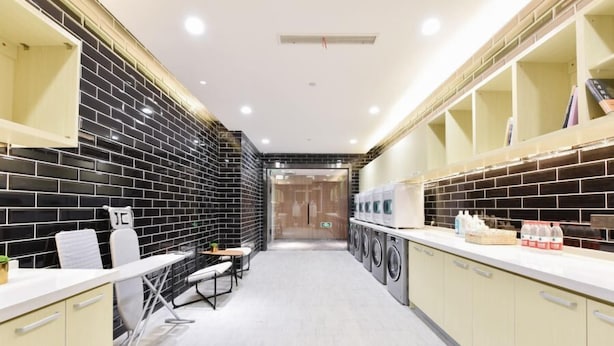 A modern laundry room with black and white tiled walls, a central washing machine area, and a seating area with a table and chairs.