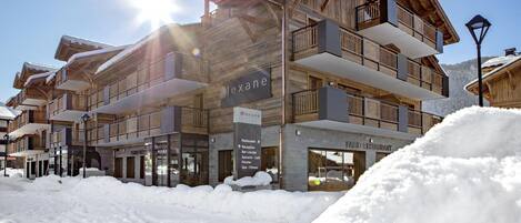 Ein mehrstöckiges Gebäude mit Holzfassade, Balkonen und einem Schild für das Restaurant 'Alexane'.