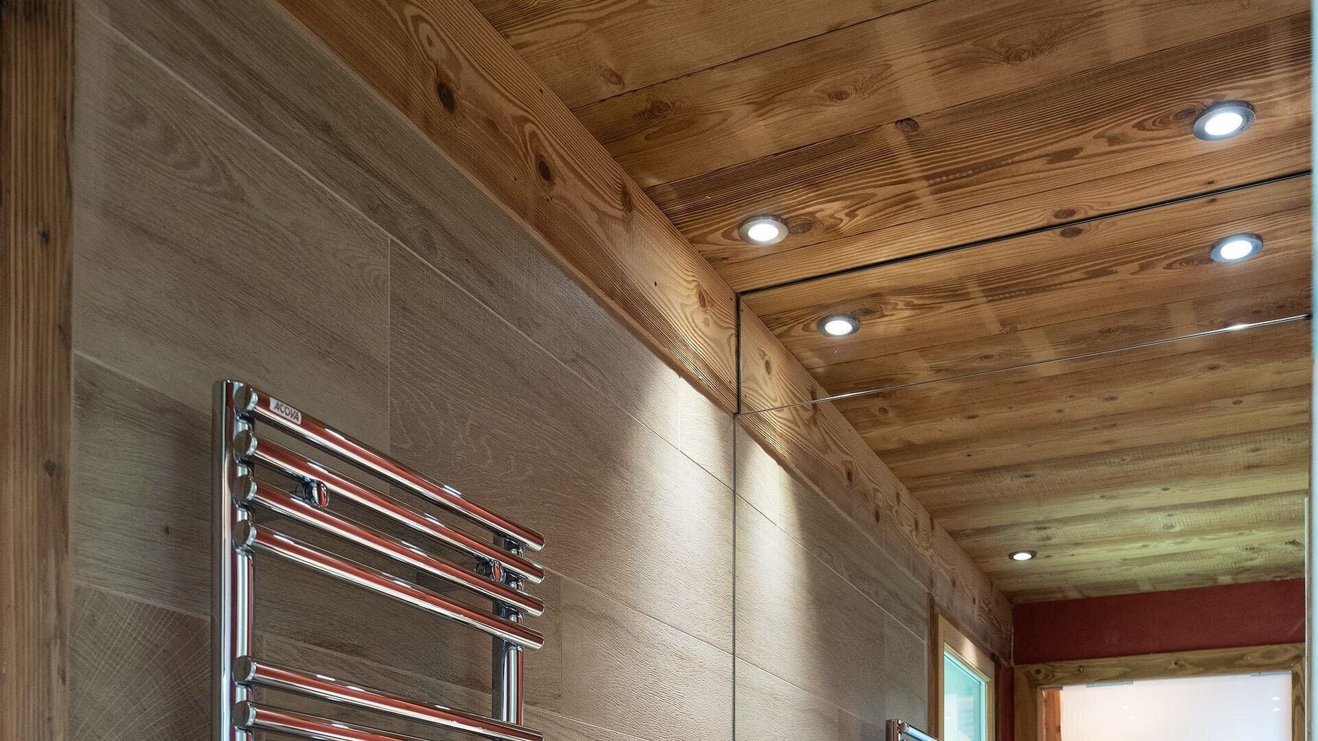 Un plafond en bois avec des spots encastrés et une étagère en métal.