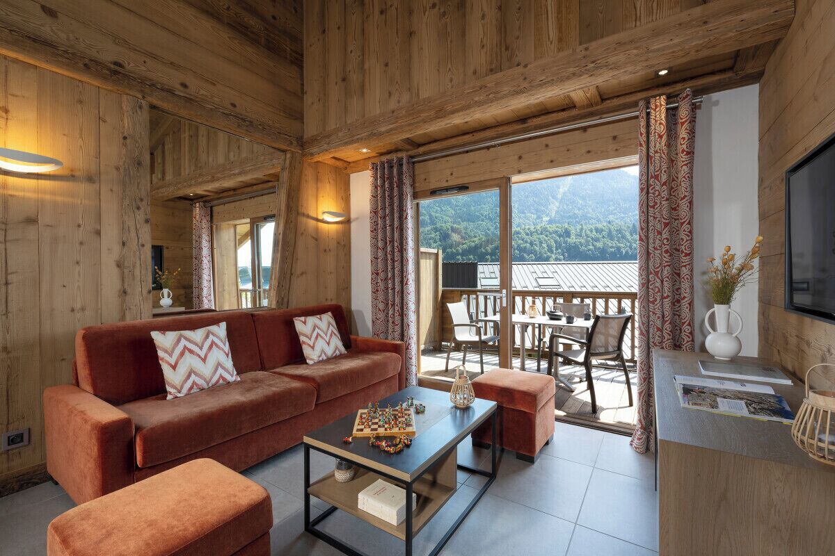 A wooden interior with a sofa, coffee table, and a dining area with chairs and a table.