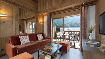 A wooden interior with a sofa, coffee table, and a dining area with chairs and a table.