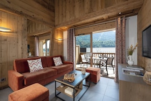 Un intérieur en bois comprenant un canapé, une table basse et un coin repas avec des chaises et une table.