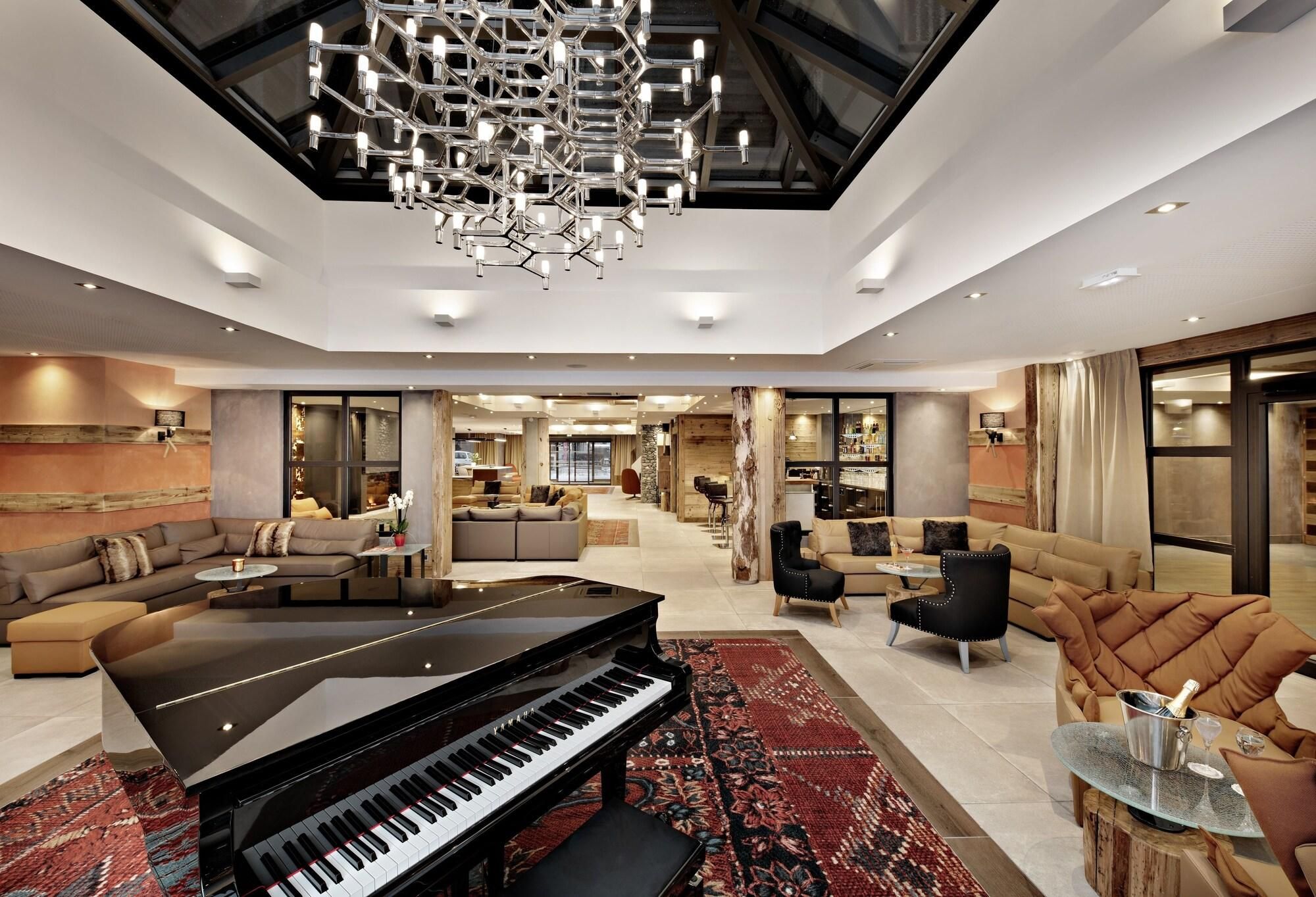 A spacious living area with a grand piano, modern furniture, and a high ceiling with a unique chandelier.