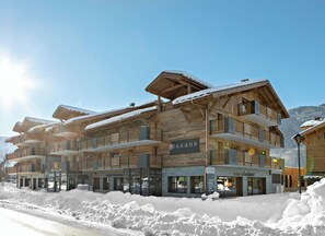 A multi-story wooden building with balconies, a sign reading 'lexane,' and a restaurant named 'FABIO RESTAURANT' at the ground level. - MGM Hôtels et Résidences - Residence Alexane (Samoëns)