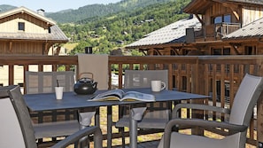 A wooden deck with a table, chairs, a kettle, and a book. - MGM Hôtels et Résidences - Residence Alexane (Samoëns)