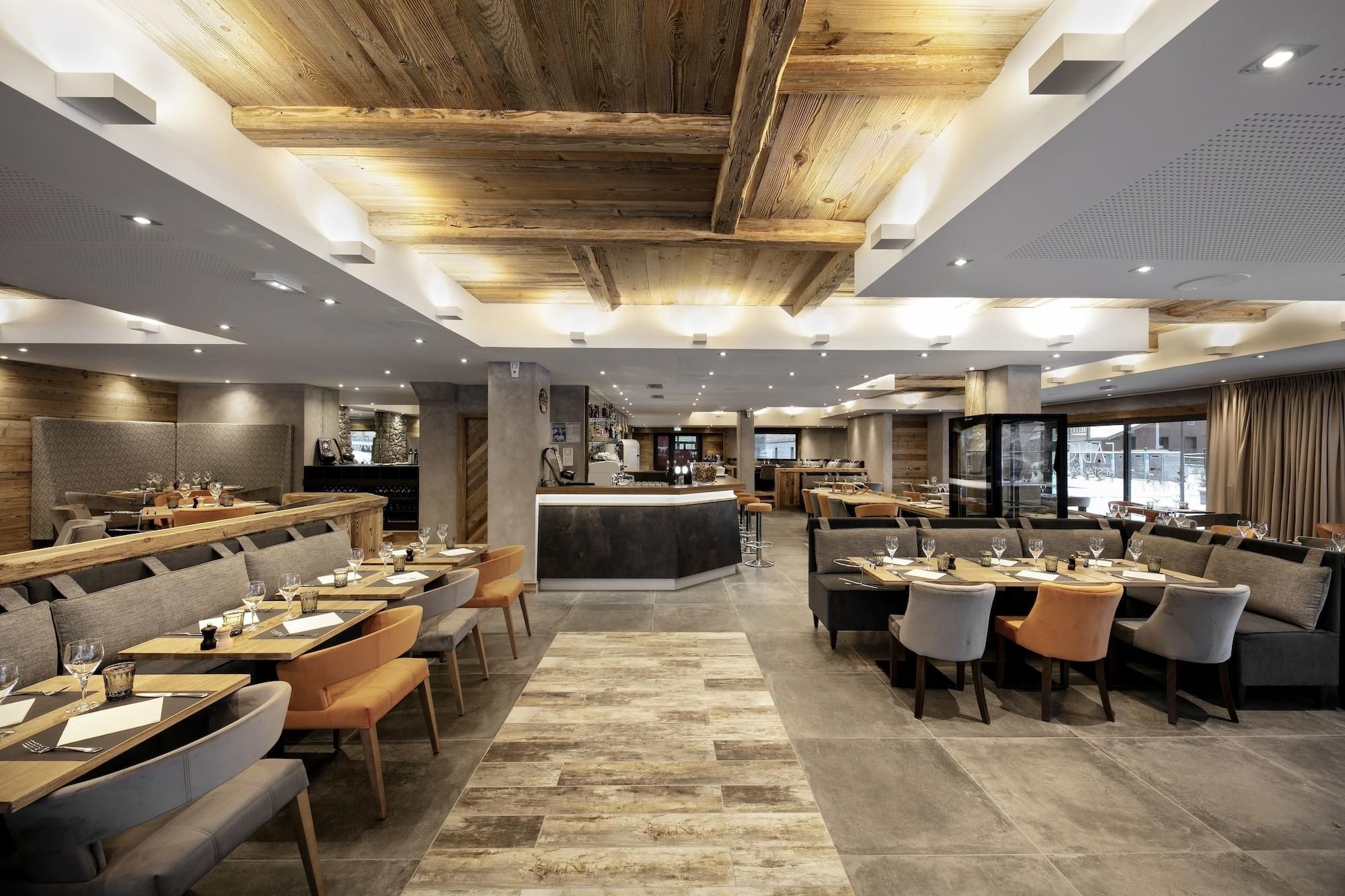 A modern restaurant with a central bar, seating areas, and a stone accent wall.