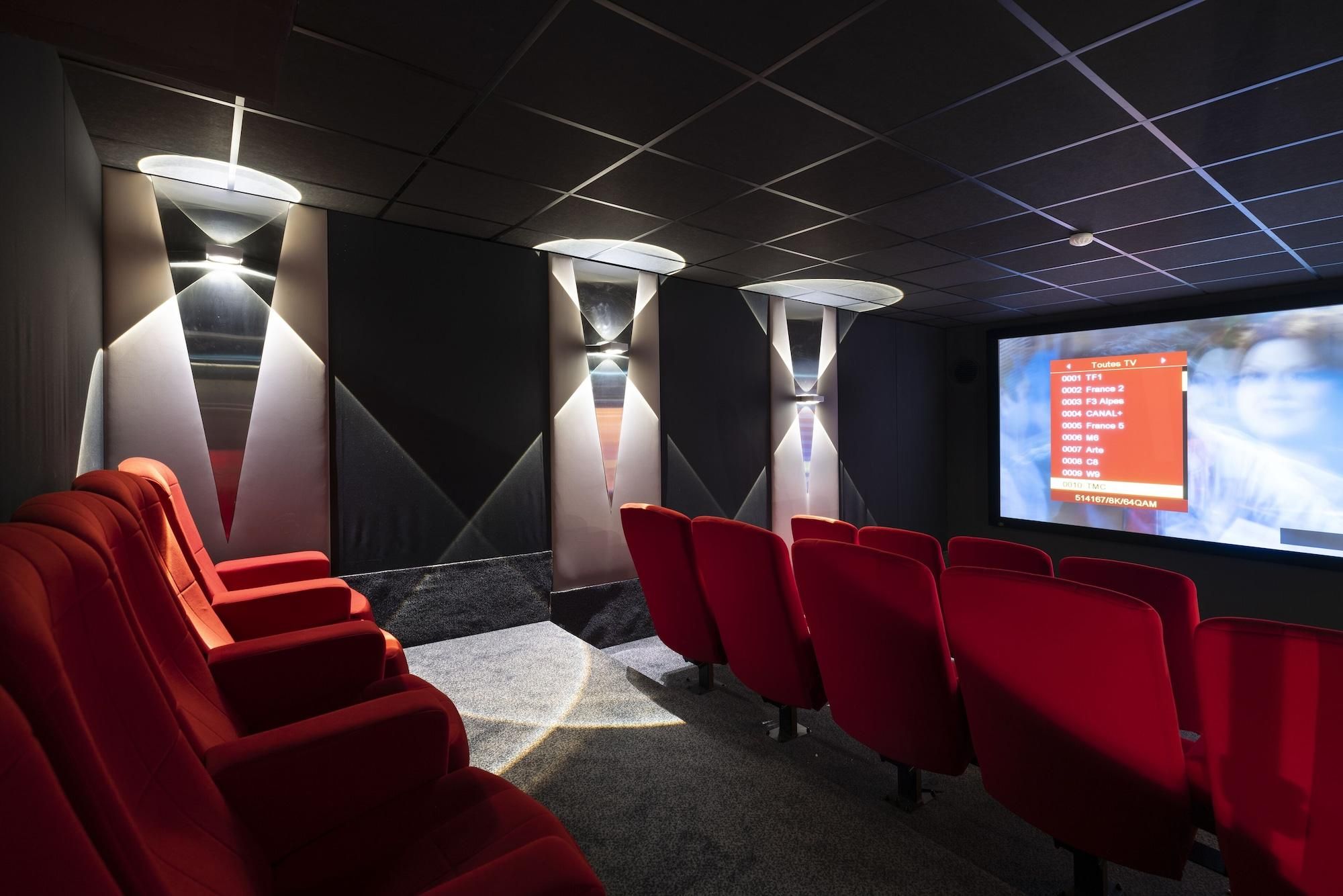 Ein Kino mit roten Sitzen und einer Leinwand, die eine Fernsehsendeliste zeigt.