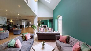 A spacious lobby with multiple seating areas, a large plant, and a view of the adjacent kitchen area. - Hotel Van Dyk (Chesterfield)