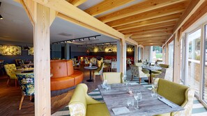 A restaurant with wooden beams, round tables, and yellow chairs. - Hotel Van Dyk (Chesterfield)
