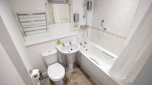 Une petite salle de bain comprenant des toilettes, un lavabo et une baignoire.