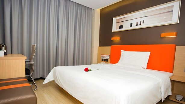 A hotel room with a bed, a desk, a chair, a wall-mounted light, and a framed picture. - 7 Days Inn Premium Beijing Dongzhimen Airport Express Station (Beijing)