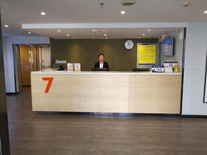 A reception desk with a number 7 sign, a clock, and informational posters. - 7 Days Inn Premium Beijing Dongzhimen Airport Express Station (Beijing)