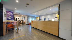 A hotel reception area with a wooden reception desk, a clock, and a poster on the wall. - 7 Days Inn Premium Beijing Dongzhimen Airport Express Station (Beijing)