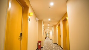 A hotel hallway with doors on both sides, a patterned carpet, and a fire extinguisher on the left. - 7 Days Inn Premium Beijing Dongzhimen Airport Express Station (Beijing)