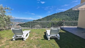 Dos sillones de relax mirando una vista panorámica de un paisaje costero con montañas al fondo.