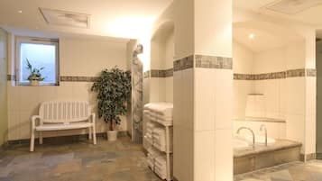 A bathroom with a bench, a potted plant, a towel rack, and a sink with a tiled backsplash.