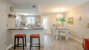 A spacious kitchen with a central island, a dining area with white chairs, and a chandelier. - Venture Out @ Gulf Highlands Beach Resort Sleeps 6 (Panama City Beach)