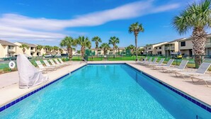 A swimming pool with lounge chairs and palm trees, surrounded by buildings. - Venture Out @ Gulf Highlands Beach Resort Sleeps 6 (Panama City Beach)