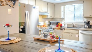 A kitchen with white cabinets, a refrigerator, a microwave, and a coffee maker. There are three dessert glasses on the table. - Venture Out @ Gulf Highlands Beach Resort Sleeps 6 (Panama City Beach)