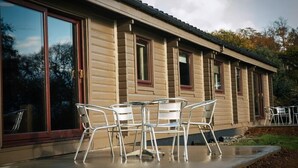 Un bâtiment moderne doté de grandes fenêtres et d’un patio aménagé avec des chaises en métal.