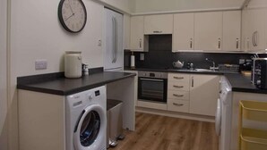 Une cuisine compacte équipée d’un lave-linge, d’une horloge et d’un four à micro-ondes.