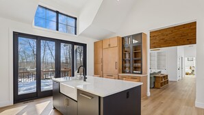 Een moderne keuken met een centraal eiland, grote ramen en uitzicht op de omgeving.