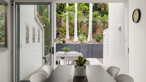 A modern patio with a dining table, chairs, and a potted plant. - Parkview on Sunshine 2 Sunshine Beach (Sunshine Beach)