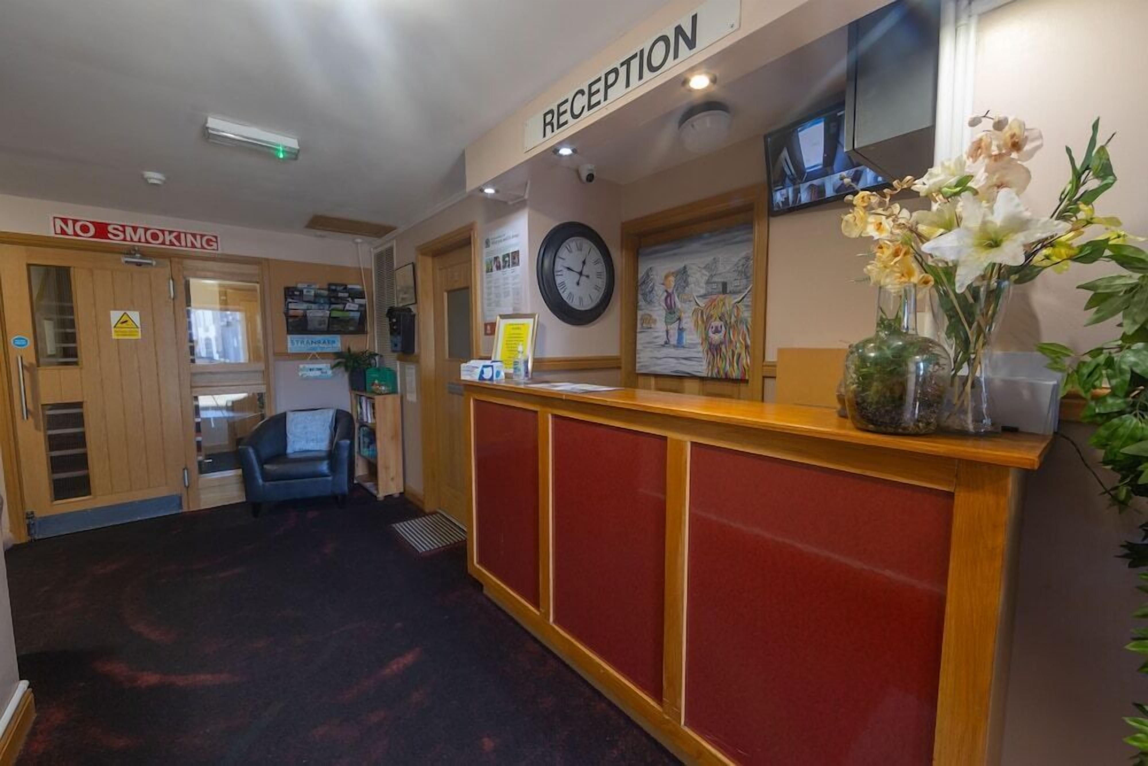 A reception area with a 'No Smoking' sign, a clock, and a reception desk.