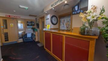 A reception area with a 'No Smoking' sign, a clock, and a reception desk.