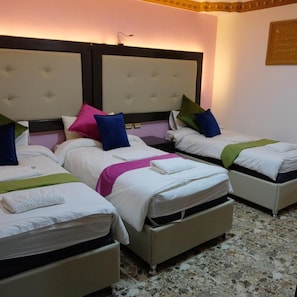 A hotel room with three beds arranged in a row, each with a headboard and pillows. - Petra Princes Hotel (Wadi Musa)
