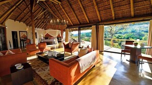 Uma sala de estar ampla com pé direito alto, uma grande janela com vista para o exterior e um agradável conjunto de assentos.