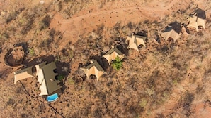 Vista aérea de um resort com vários edifícios dispostos em linha ao longo de uma estrada de terra.
