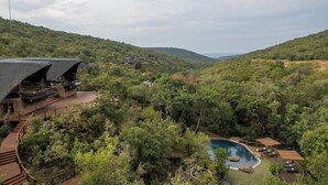 Um resort com piscina, rodeado por vegetação exuberante e colinas.