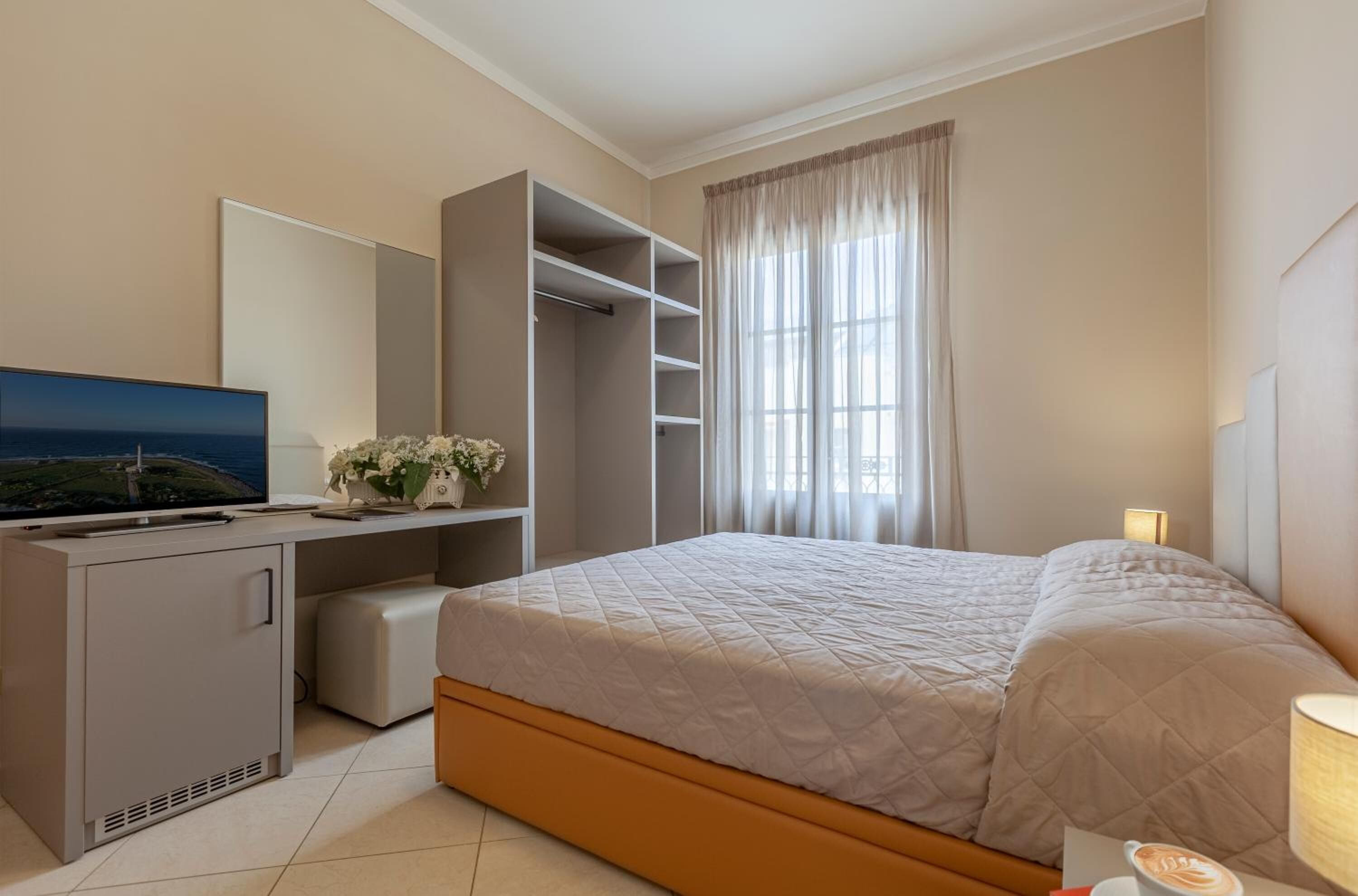 Une chambre d’hôtel équipée d’un lit, d’un bureau, d’une télévision et d’une armoire.