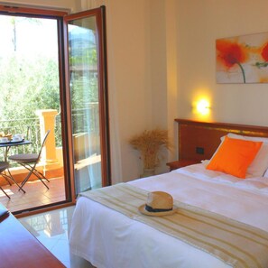 A hotel room with a bed, a dining table with chairs, a sliding glass door to an outdoor area, and a painting on the wall. - Hotel Piccolo (Parghelia)
