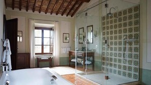 Een badkamer met een groot bad, een douchecabine met glazen wanden en een betegelde muur met een geometrisch patroon.