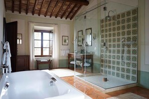 Une salle de bain dotée d’une grande baignoire, d’une douche à parois de verre et d’un mur recouvert de carreaux formant un motif géométrique.