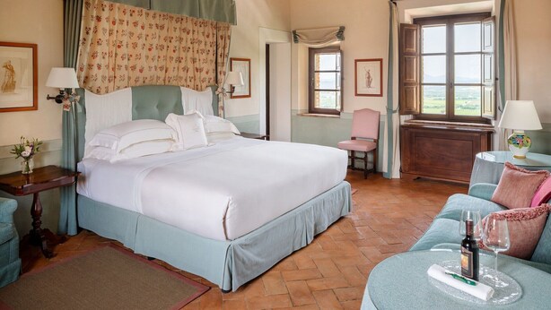 Een slaapkamer met een groot bed, een bureau, een stoel en een raam met uitzicht.