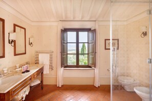 A bathroom with a large window, a sink, a mirror, and a toilet. - Castello Banfi (Montalcino)