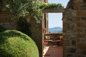 A stone archway leading to a patio with a view of a hill. - Castello Banfi (Montalcino)