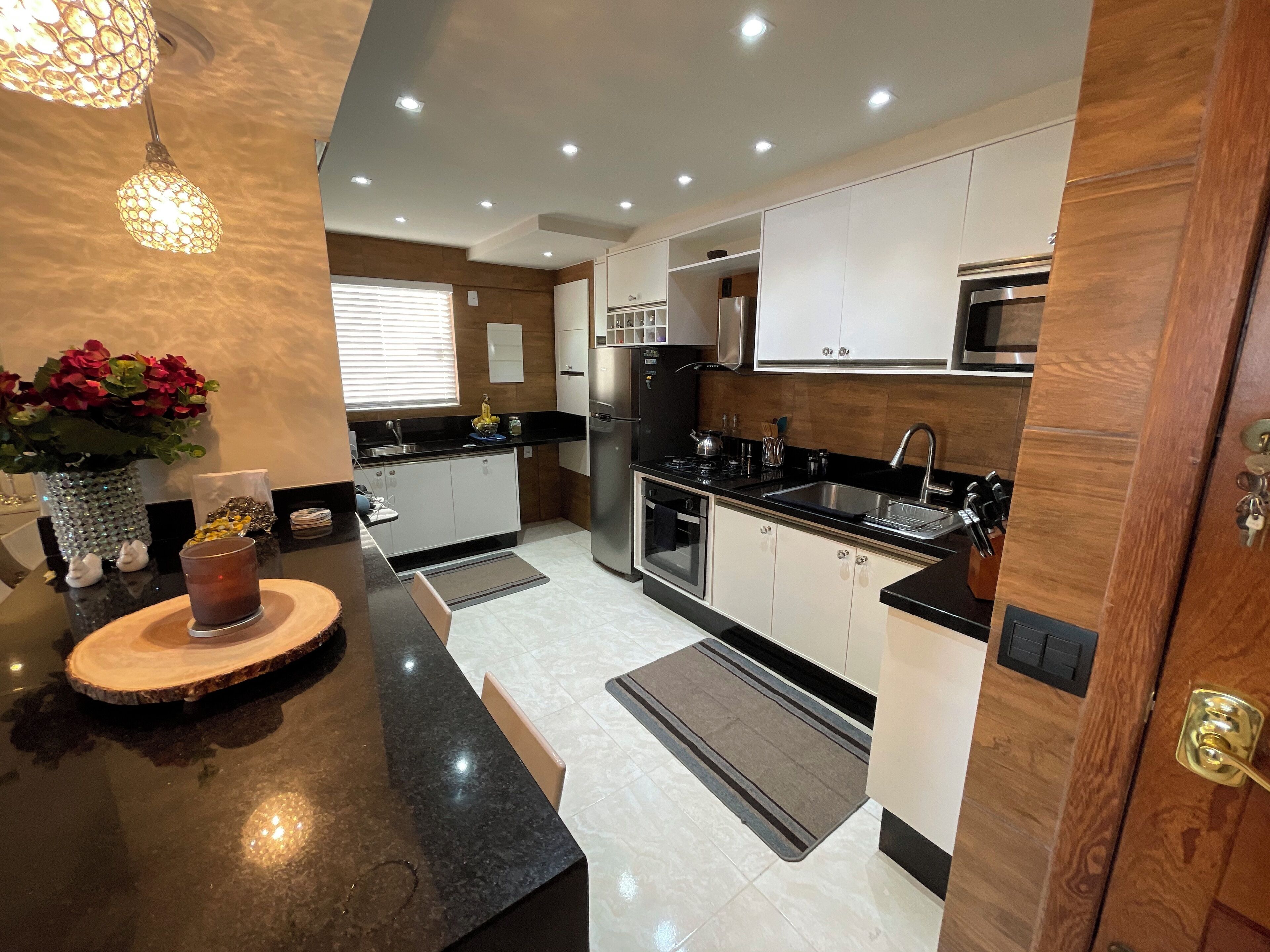 A modern kitchen with a black countertop, stainless steel appliances, and wooden cabinets.