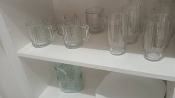 Un estante blanco con varios vasos y recipientes de almacenamiento.