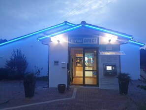 Ein Gebäude mit einem Schild, auf dem 'Kyriad DIRECT' steht, und einem durch die Glastüren einsehbaren Empfangsbereich.