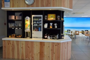 Eine Theke mit einem Kühlschrank, Regale mit Lebensmitteln und Blick auf den Strand.
