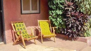 Two wooden chairs with green and yellow patterned cushions outside a building with a red wall and a window. - Maya (Cap Skirring)