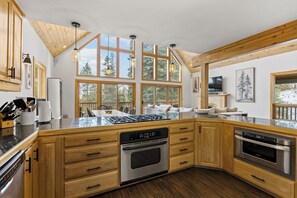 A modern kitchen with wooden cabinets, a central island, stainless steel appliances, and large windows offering views of the outdoors. - 5-Acre Durango Home | Trails, Deck, Mesa Verde (Durango)
