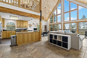 A spacious kitchen with wooden cabinets, a central island, and large windows offering a view of the outdoors. - 5-Acre Durango Home | Trails, Deck, Mesa Verde (Durango)